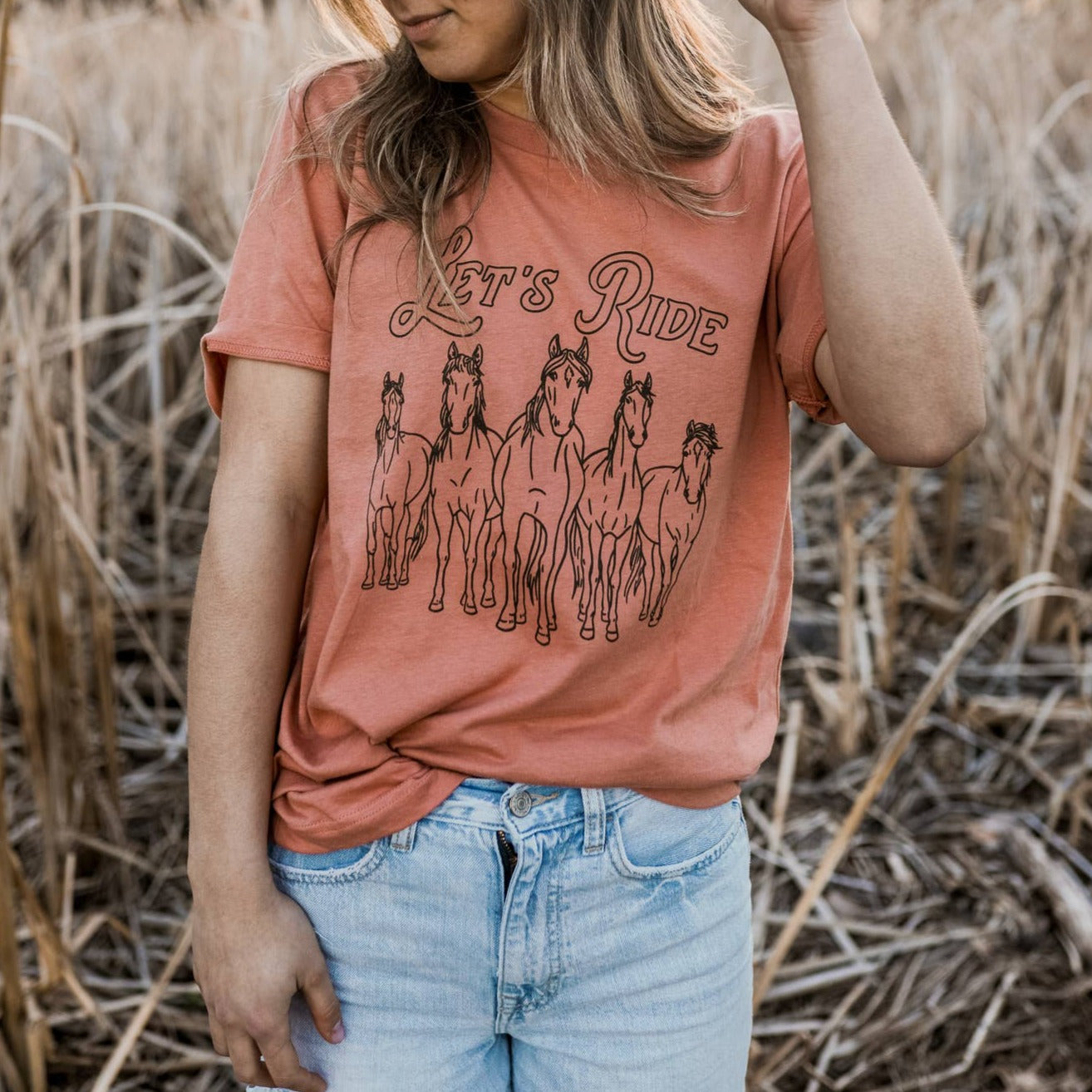 Terracotta t-shirt with "let's ride" in black lettering. 5 wild horses in black underneath