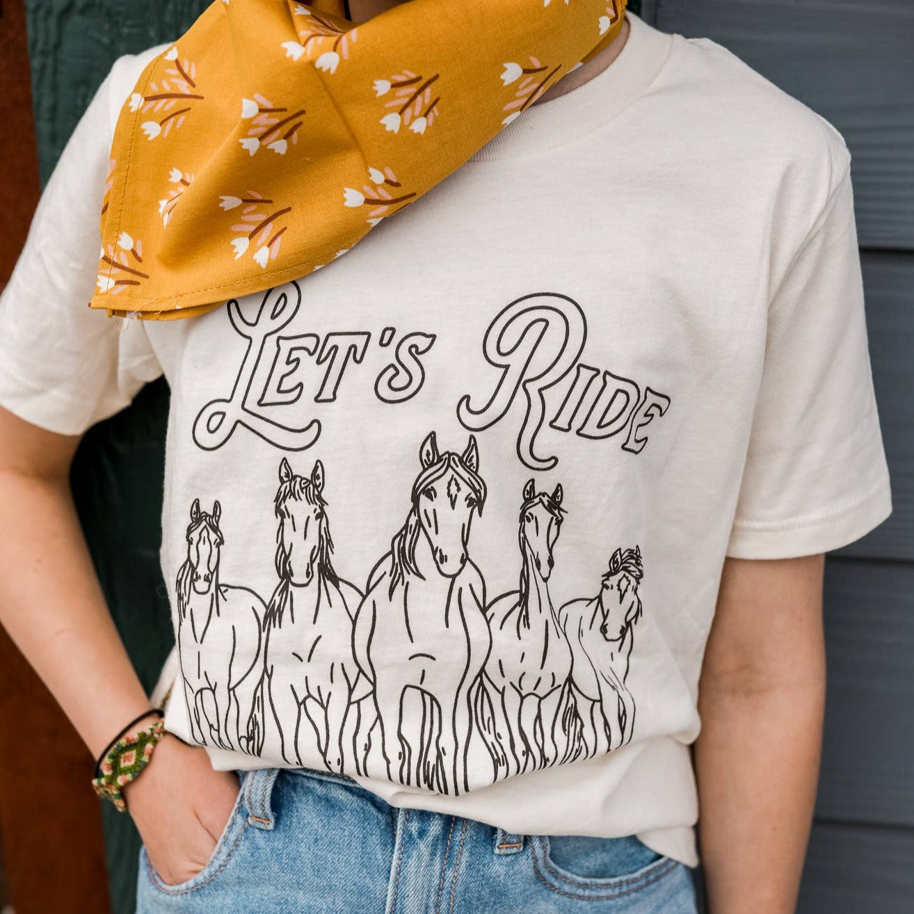 White t-shirt with "let's ride" in black lettering. 5 wild horses in black underneath