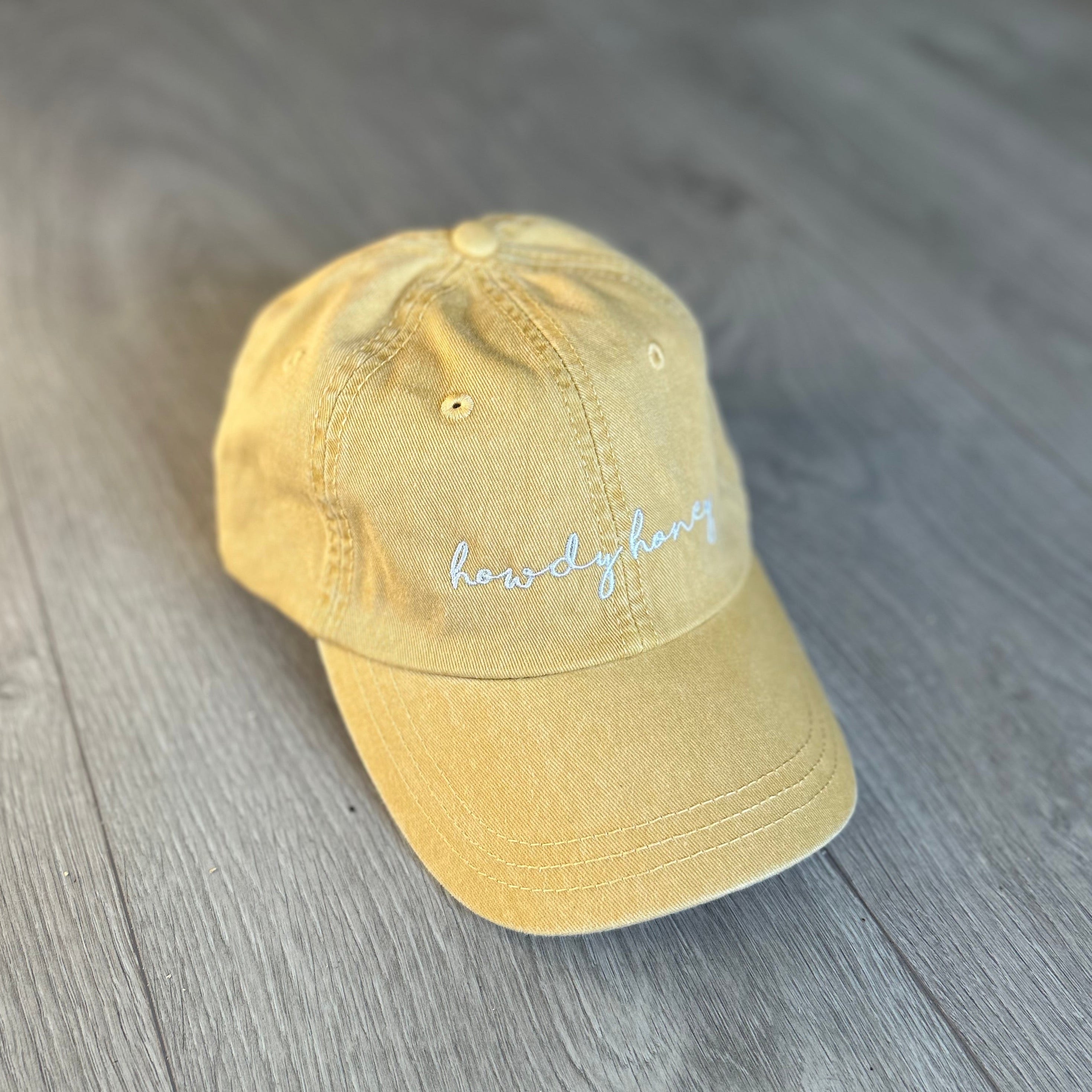 Yellow baseball cap with embroidered text "Howdy Honey" in white 