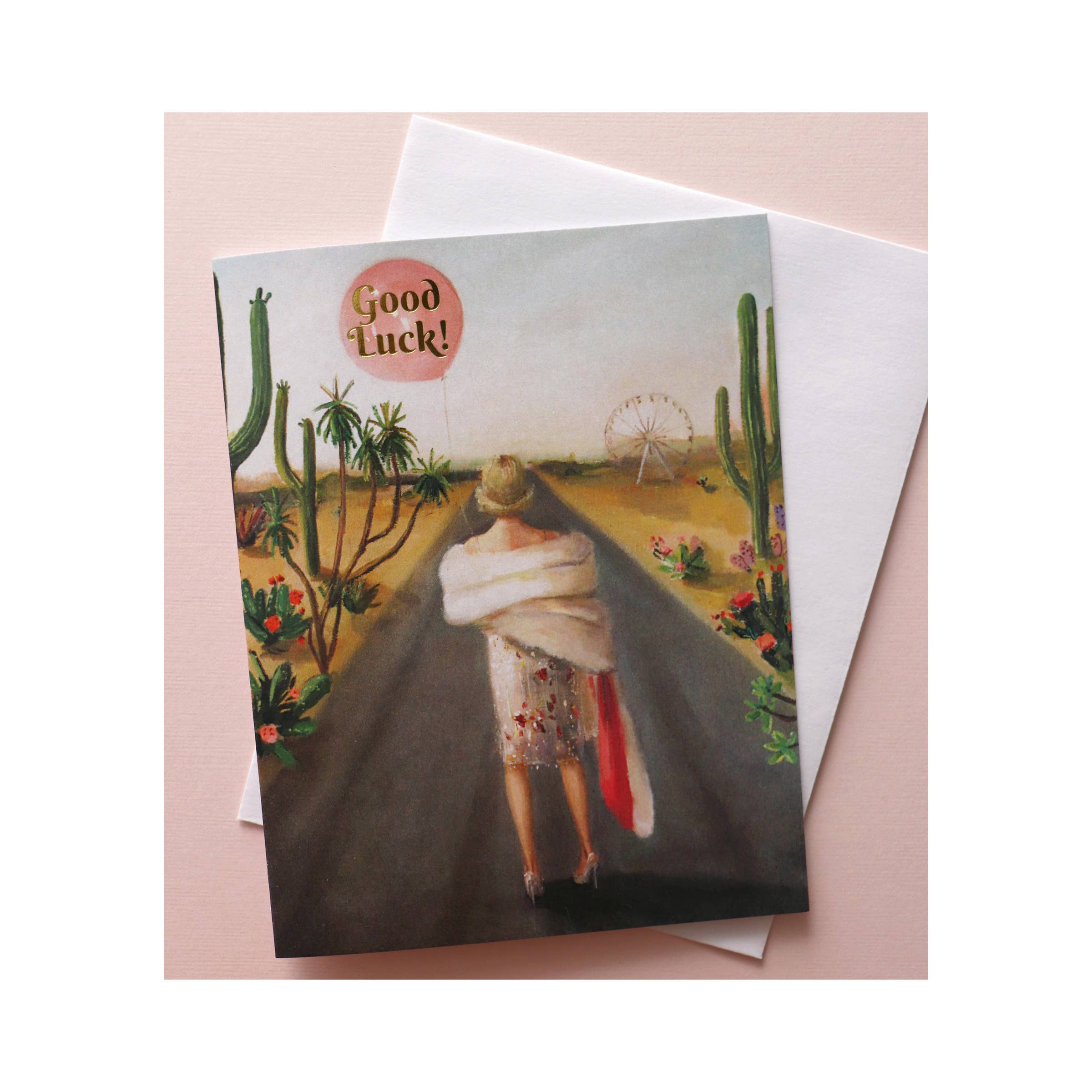 Greeting card with lady dressed in party wear, walking down desert road. Says "good luck" in pink umbrella she is holding